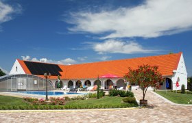 Margaréta Pension, © Margaréta Csárda Ein weißes Gebäude mit rotem Dach und typisch ungarischem Bogengang, davor ein Garten mit Pool.