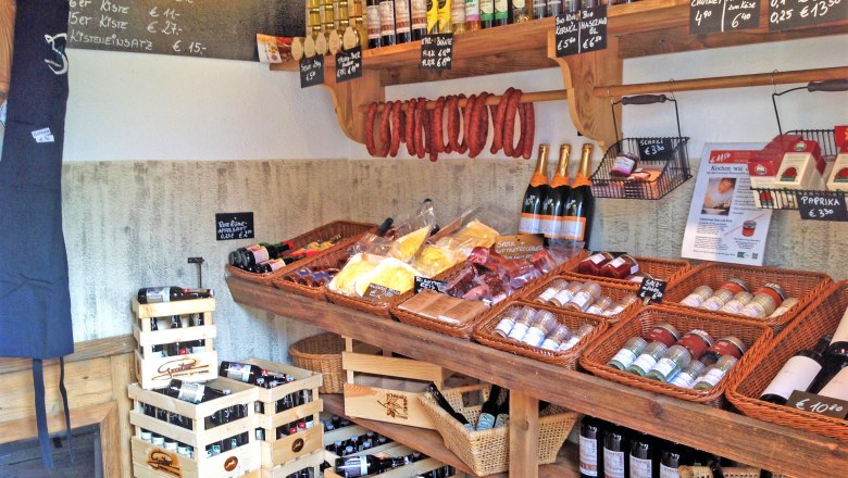 Triad´s Hofladen, © Triad Innenansicht eines Hofladens mit Regalen voller regionaler Produkte wie Wein, Wurst, Gewürze und Öl.