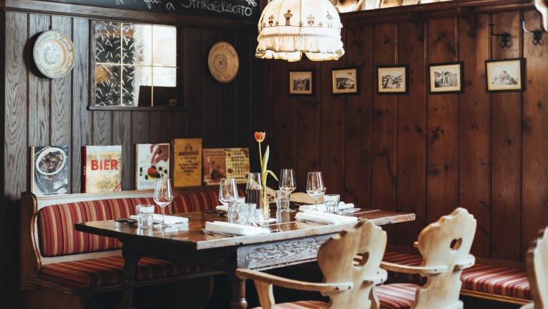 Gaststube im Hotel Post Hönig, © Niederösterreich Werbung/David Schreiber Gemütliches Restaurant mit Holzwänden, rot gestreiften Sitzbänken und gedecktem Tisch.