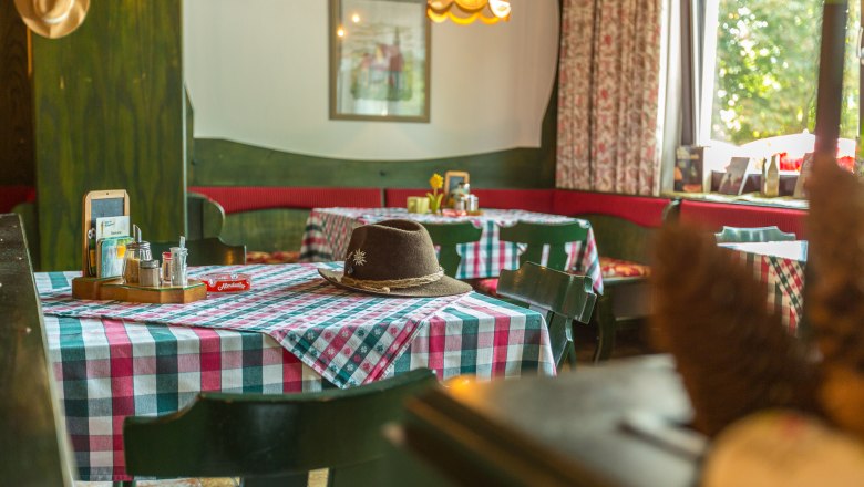 Gaststube, © Wiener Alpen / Christian Kremsl Gemütliche Gaststube mit karierten Tischdecken und einem Hut auf dem Tisch.