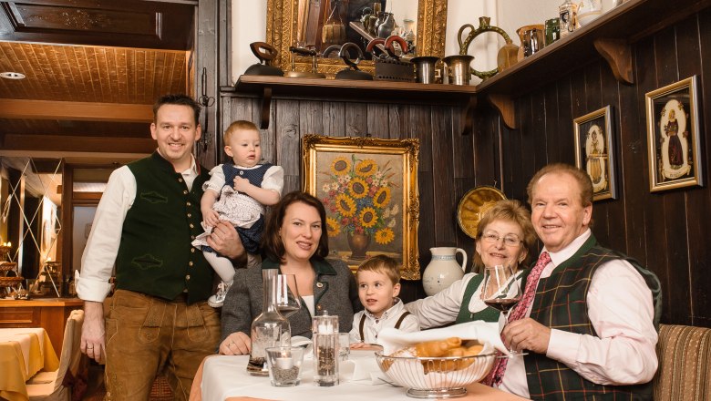 Hotel Post-Hönigwirt, © Niederösterreich Werbung/Rita Newman Eine Familie in traditioneller Kleidung sitzt an einem Tisch in einem rustikalen Restaurant.