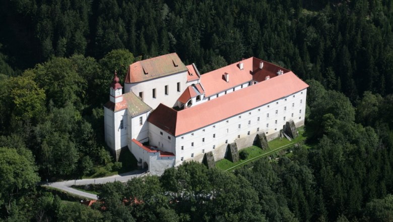 Festenburg, © Archiv Stift Vorau Luftaufnahme einer Burg mit roten Dächern, umgeben von Wald.