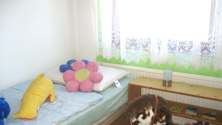 Schlafzimmer 3, © Anke Spreitzer Kinderzimmer mit Bett, Plüschtieren und Spielzeugpferd.