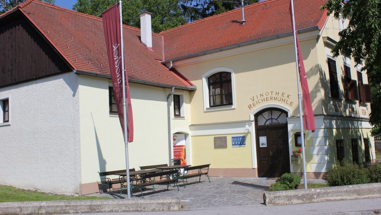 Vinothek Reichermühle, © Gemeinde Rechnitz, Gager Erich Gebäude mit gelber Fassade und roten Dachziegeln. Über dem Eingang steht "Vinothek Reichermühl"e