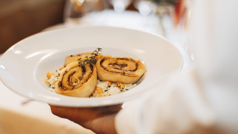 Porcini gomba roulade, © Niederösterreich Werbung/David Schreiber Egy tányér porcsinigombás rouládét tálalnak fel, gyógynövényekkel díszítve.