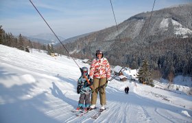 Skilifte Feistritzsattel, © Wiener Alpen, Foto: Franz Zwickl Zwei Skifahrer auf einem Schlepplift in einer verschneiten Berglandschaft.