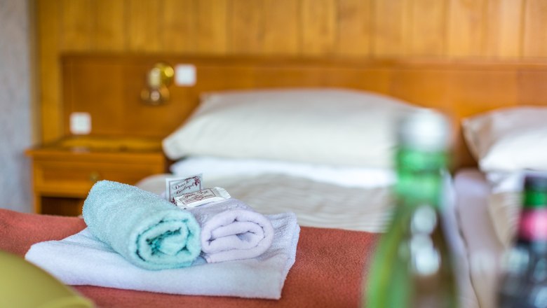 Zimmer, © Wiener Alpen / Christian Kremsl Hotelzimmer mit Bett, Handtüchern und Wasserflaschen.