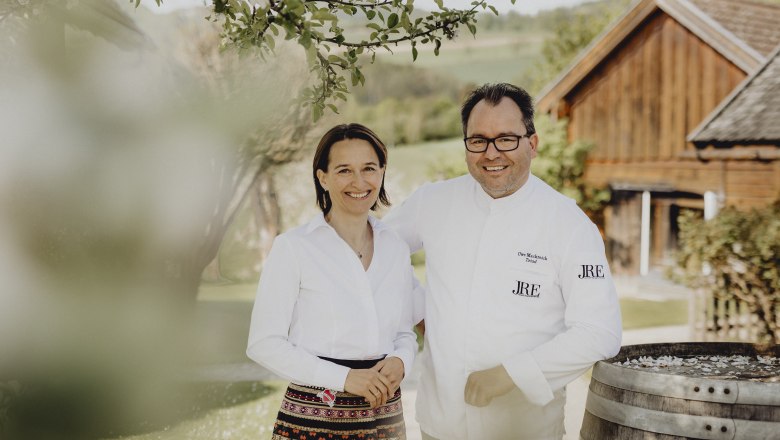 Veronika und Uwe Machreich, © Niederösterreich Werbung/Sophie Menegaldo Ein Mann und eine Frau stehen lächelnd im Freien vor einem Holzgebäude.