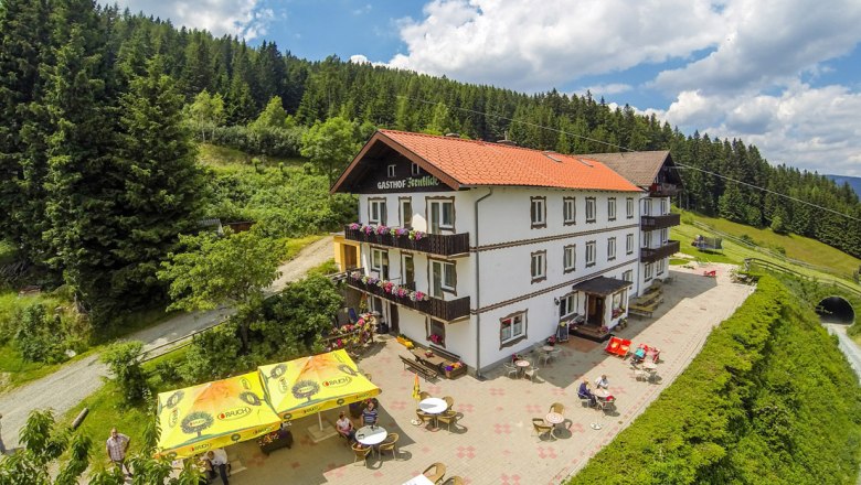 Alpengasthof Fernblick, © Wiener Alpen, Foto: Franz Zwickl Alpengasthof mit Terrasse und Sonnenschirmen in bergiger Landschaft.