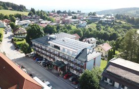 Luftbild Hotel Thier, © Franz Thier Luftaufnahme eines Hotels mit Solarpanelen auf dem Dach, umgeben von Bäumen und weiteren Gebäuden in einer ländlichen Gegend.