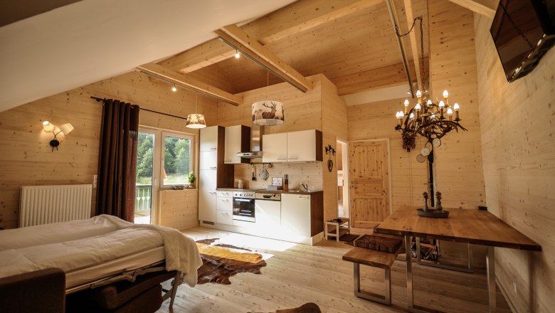 Stájer apartman, © Stefan Zimprich Hangulatos lakás fából készült falakkal, konyhával, étkezőasztallal és ággyal.