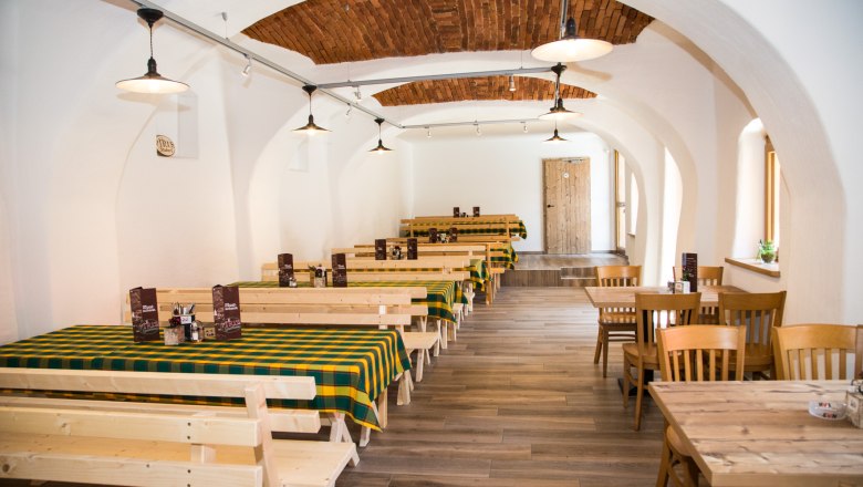 Szalon, © Christian Piribauer Egy fogadó hagyományos belső tere, faasztalokkal és kockás terítőkkel.