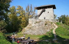 Óház Aussichtsturm, © Walter Laschober Steinerner Turm auf einem Hügel mit Picknicktischen im Vordergrund.