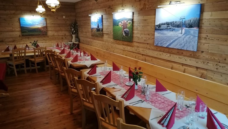 Der Saal für Festlichkeiten, © Alpengasthof Fernblick, Fam. Pölzelbauer Ein festlich gedeckter Saal mit Holzwänden, dekoriert mit Bildern und roten Servietten auf den Tischen.