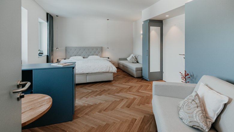 Erholung in den neuen gemütlichen Zimmern, © Der Löffler - Nicole Seiser Modern eingerichtetes Hotelzimmer mit Doppelbett, Sofa und Holzboden.