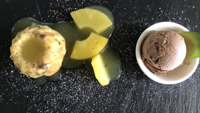 Das Leitner - Narnhoferwirt, © Tourismusverband Oststeiermark, Karin Leitner Dessert mit Kuchen, Ananas und Schokoladeneis auf schwarzem Teller.