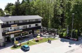 A Gasthof Berghof k&uuml;lső n&eacute;zete, terasz &eacute;s parkol&oacute;, f&aacute;kkal k&ouml;r&uuml;lv&eacute;ve.