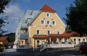 Gelbes Hotelgebäude mit rotem Dach und modernen Balkonen.