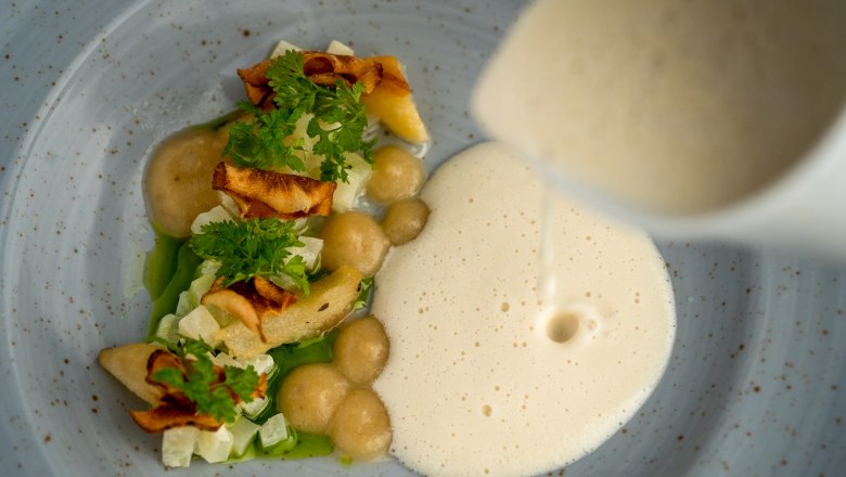 Gourmetgericht mit Schaum und Gem&uuml;se auf einem Teller.