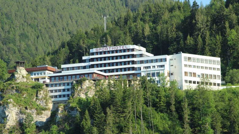 A Sporthotel am Semmering, © Sporthotel Semmering Egy nagy, modern szállodaépület egy erdős dombon.