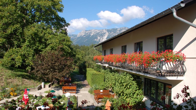 Gasthof mit Balkon voller Blumen und Bergblick.