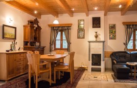 Gemütliches Zimmer mit Holzmöbeln, Esstisch, Kamin und Ledersofa.