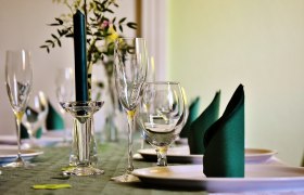 Eleganter Tisch mit Weingläsern, Kerze und gefalteten Servietten.