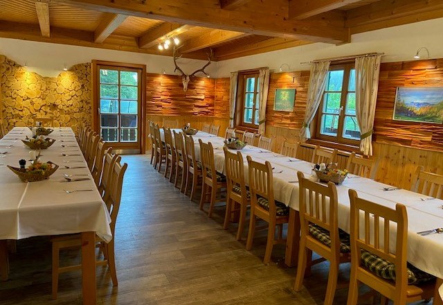 Rusztikus &eacute;tkező hossz&uacute;, ter&iacute;tett asztalokkal &eacute;s f&aacute;b&oacute;l k&eacute;sz&uuml;lt falakkal.