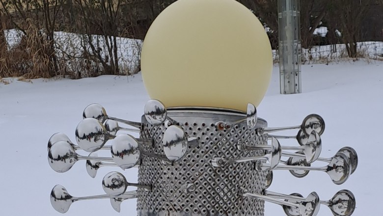 Eine Skulptur im Schnee mit einer kugelf&ouml;rmigen Lampe und metallischen Elementen.