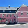 Ein altrosa Geb&auml;ude mit mehreren Fenstern und dem Eingangsbereich..