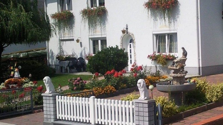 Ein wei&szlig;es Haus mit Blumenk&auml;sten und gepflegtem Garten.