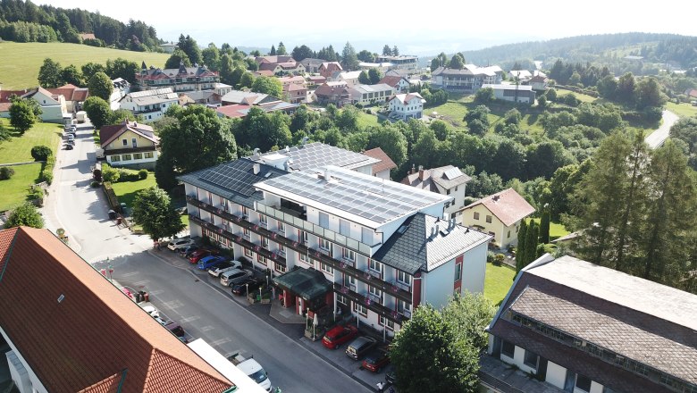 Luftbild_Hotel_2026, © Franz Thier Légi felvétel egy szállodáról, amelynek tetején napelemek vannak, és amelyet fák és más épületek vesznek körül egy vidéki környezetben.