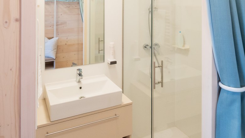 Modernes Badezimmer mit Waschbecken, Spiegel, Dusche und blauen Vorh&auml;ngen.