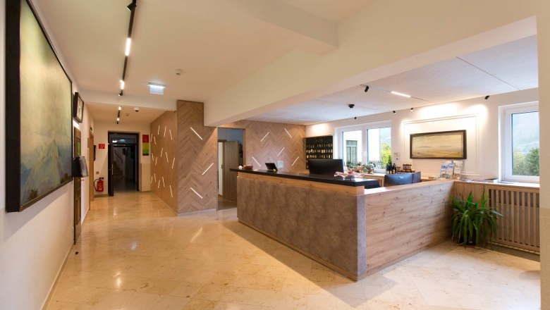 Rezeption eines Hotels mit modernem Design, Holzelementen und einem gro&szlig;en Empfangstresen.