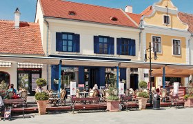 Straßencafé vor einem gelben Gebäude mit rotem Dach.