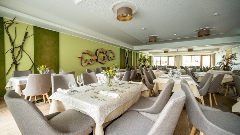 Elegantes Hotelrestaurant mit gedeckten Tischen und grauen St&uuml;hlen.