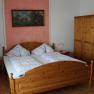 Ein Schlafzimmer mit einem Doppelbett, zwei Nachttischen, einem Kleiderschrank und einem Gem&auml;lde an der Wand.