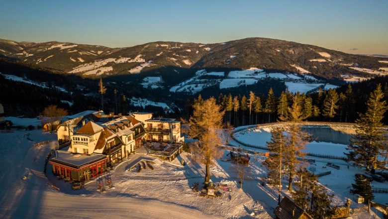 Alpengasthof Enzian in verschneiter Berglandschaft bei Sonnenuntergang.