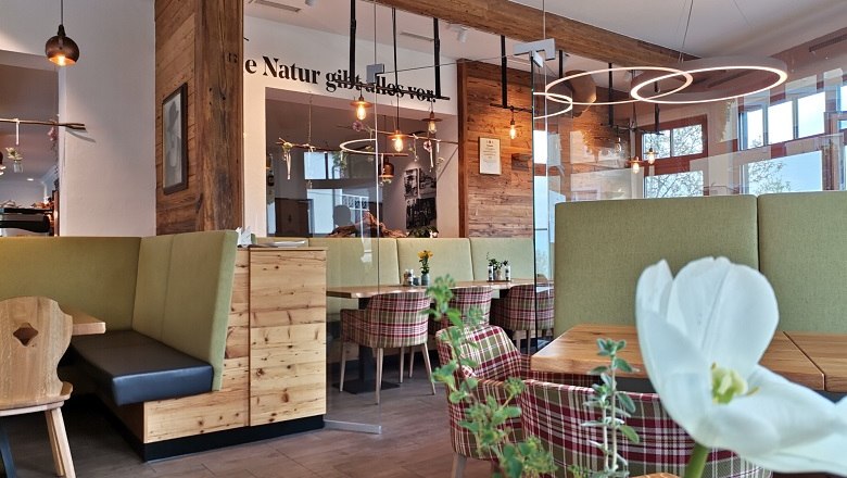 Innenansicht einer gemütlichen Bäckerei mit Holzmöbeln und modernen Leuchten.