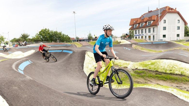 Kinder fahren mit Fahrrädern auf einer Pumptrack-Strecke in Wiener Neustadt.