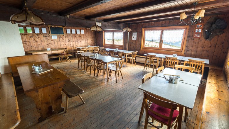 Gemütliche Holzhütte mit Tischen und Stühlen, rustikale Einrichtung.