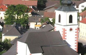 Pfarrkirche Hochneukirchen mit umliegenden Gebäuden und Landschaft.