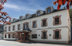 Historisches Geb&auml;ude mit dekorativen Fensterrahmen und Schildern f&uuml;r Hotel und Restaurant.