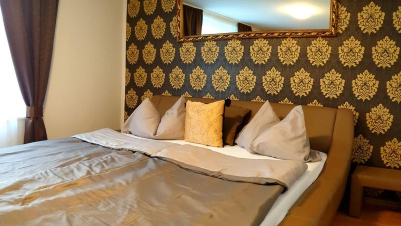 Ein gemütliches Hotelzimmer mit einem großen Bett, dekoriert mit goldenen Mustern an der Wand und einem Spiegel darüber.