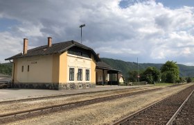 Bahnhof Aggsbach-Markt mit Gleisen und bew&ouml;lktem Himmel.
