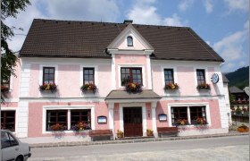 Ein traditionelles Gasthaus mit rosa Fassade und Blumenkästen an den Fenstern.