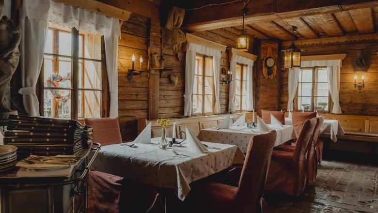 Innenansicht eines rustikalen Restaurants mit Holzw&auml;nden und gedeckten Tischen.