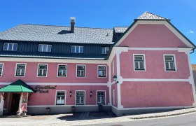 Ein altrosa Geb&auml;ude mit mehreren Fenstern und dem Eingangsbereich..