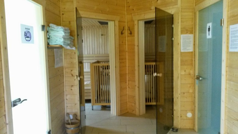 Innenansicht einer Sauna mit Holzw&auml;nden, Glast&uuml;ren und Handt&uuml;chern.