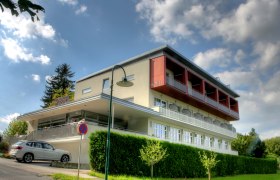 Modernes zweistöckiges Gebäude mit Balkonen in Hanglage.